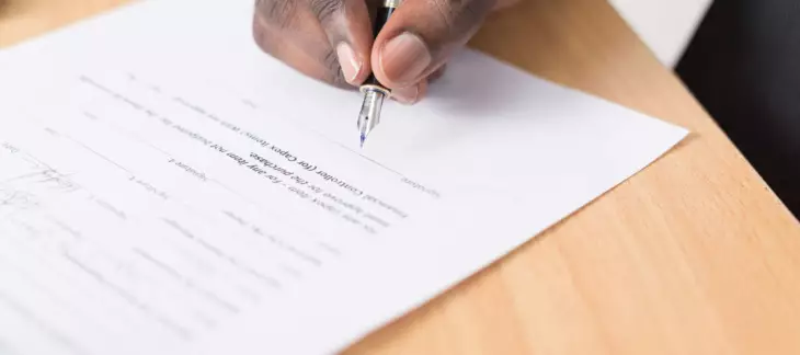 Hand holding a pen and signing a contract