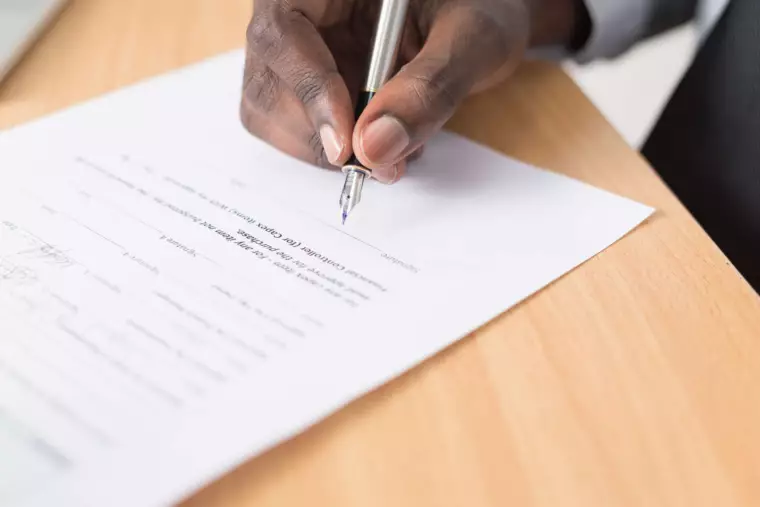 Hand holding a pen and signing a contract